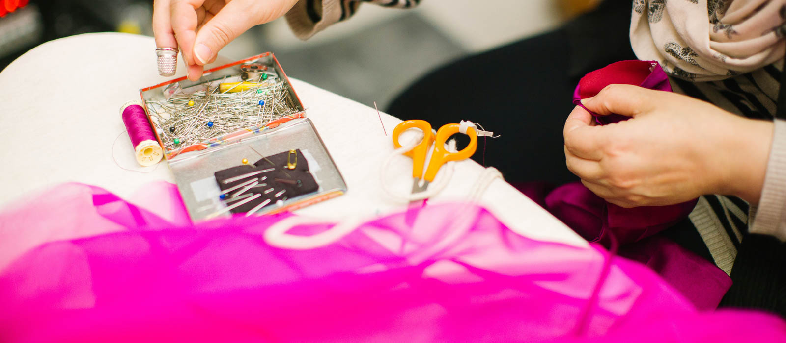 Sewist holding the sleeve of a pink garment and pins